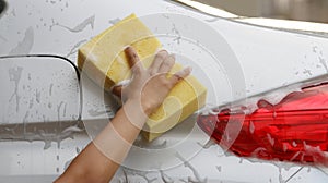 Woman Washing a car with a sponge and soap.