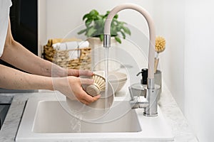 Woman washing ceramic dishes using eco-friendly brush