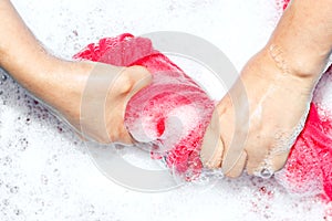 Woman washing clothes by hand with detergent in plastic bowl