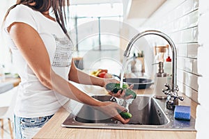 Woman washing cucumbers in kitchen sink close up.