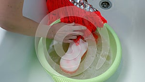 Woman is washing dance dress in basin in soapy water, laundry by hands.