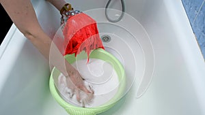 Woman is washing dance dress in basin in soapy water, laundry by hands.