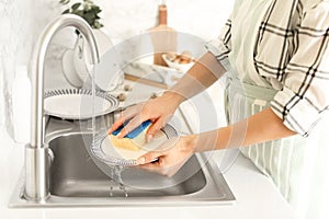 Woman washing dishes in kitchen sink