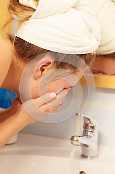 Woman washing face in bathroom. Hygiene