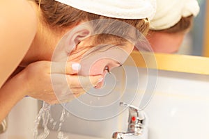 Woman washing face in bathroom. Hygiene