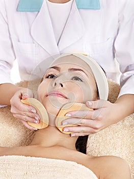 Woman washing face by sponge.