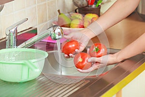 Woman washing fresh vegetables in kitchen