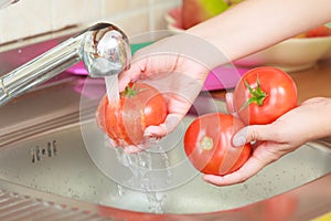 Woman washing fresh vegetables in kitchen