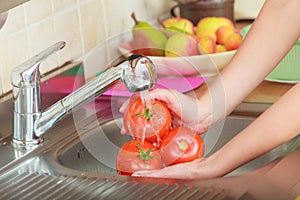 Woman washing fresh vegetables in kitchen