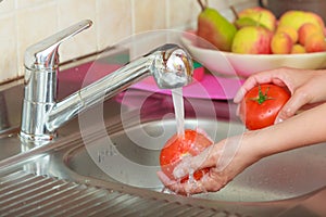 Woman washing fresh vegetables in kitchen