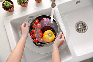 Woman washing fresh vegetables in kitchen sink, top view