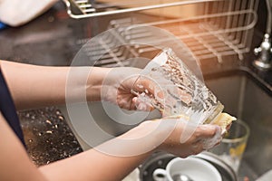 A woman washing glass by dish soap