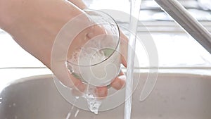 Woman washing a glass with soap by hand