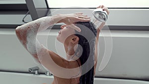 Woman washing hair in bathroom, slow-motion shower scene.