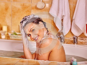 Woman washing hair in bubble bath