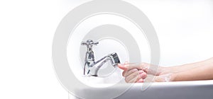 Woman washing hand with soap foam and tap water in bathroom. Hand clean under faucet on sink for personal hygiene to prevent flu