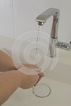 Woman washing hand under running water