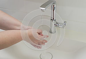 Woman washing hand under running water