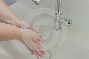 Woman washing hand under running water