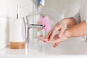 Woman washing hands in bathroom due to corona virus pandemic