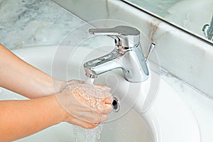 Woman washing hands at modern marble bathroom