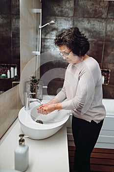 woman washing hands with soap and sanitiser in bathroom, details of hygiene, disinfecting hands