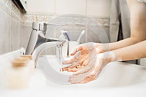 Woman washing hands with soap and water in clean bathroom.Decontamination protocol,hand hygiene routine.Cleaning hands regularly.