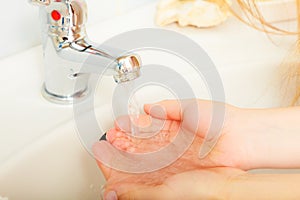 Woman washing hands under flowing tap water