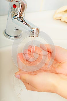 Woman washing hands under flowing tap water