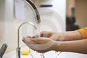 Woman washing hands under the water tap.