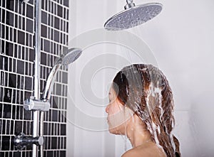 Woman washing head and hair in the rain shower by shampoo