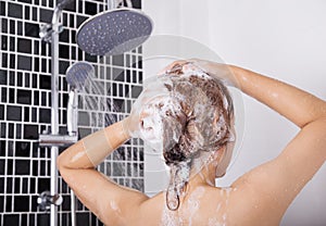 Woman washing head and hair by shampoo, rear view