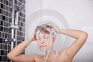 Woman washing head and hair in the shower by shampoo