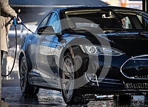 Woman washing her car in a manual carwash