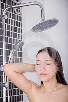 Woman is washing her hair and face by rain shower