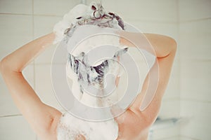 woman washing her hair with a lot of foam inside a shower box