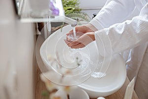 Woman washing her hands with soap in bathroom