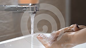 Woman washing her hands with soap in the bathroom. Smear the soap on hands. Bubbles of foam. Slow motion.