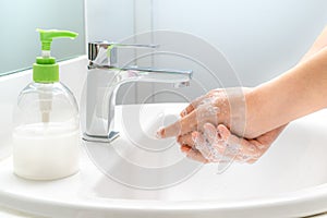 Woman washing her hands with soap at the sink for good hygiene and cleanliness