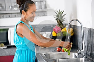 Woman washing lettuce in the kitchen sink