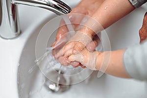 woman washing little baby boys hands. Hygiene and disinfection of hands at home with soap and tap water