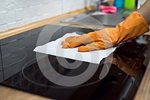 Woman washing modern  cooktop cooking panel in kitchen