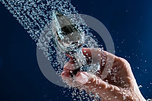 Woman washing silver anal plug under shower on blue background.