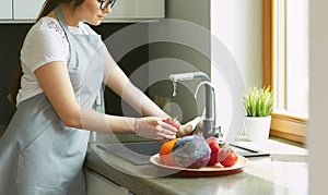 Woman washing tomatoes in kitchen sink close up