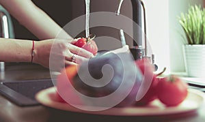 Woman washing tomatoes in kitchen sink close up