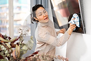 Woman washing TV monitor during cleanup