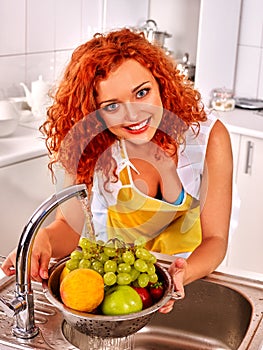 Woman washing vegetables at kitchen.