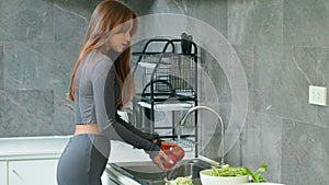 A woman is washing vegetables in the kitchen sink