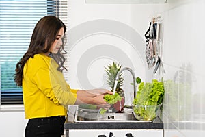 Woman washing vegetables in the sink in the kitchen at home