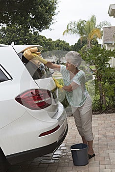 Woman washing the windscreen of a white saloon car